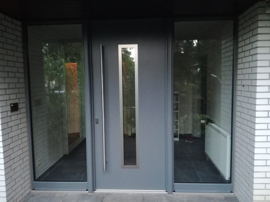 Neue anthrazitfarbene Haustür mit Glaselementen nach der Sanierung
